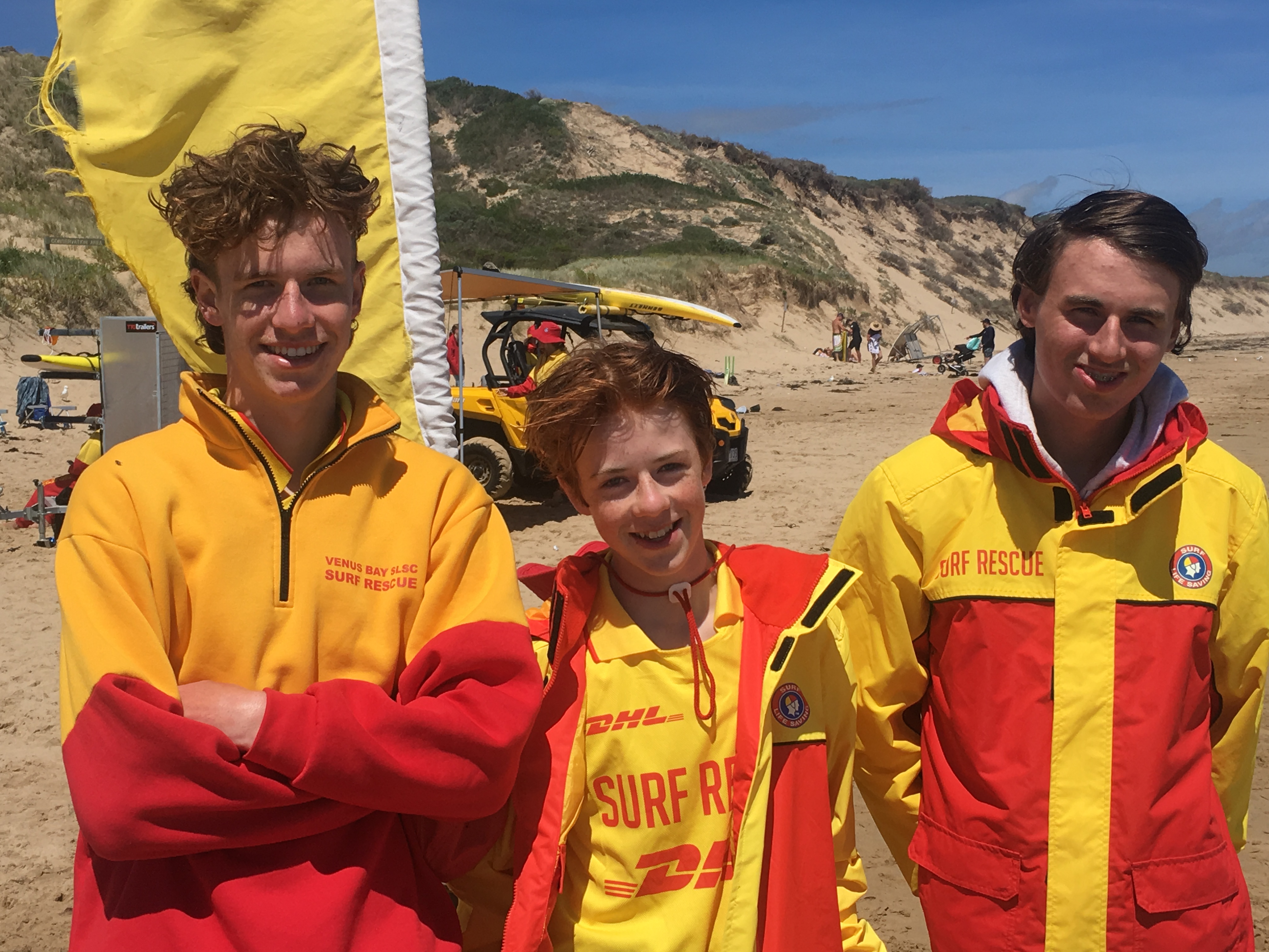 Linus Smith, left, in a Venus Bay Surf Life Saving Club rescue jacket on the beach with two fellow surf lifesavers
